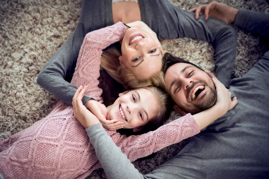 Happy family smiling to the camera lying on the floor with Affordable Insulation Choices for a cozy and joyful home.