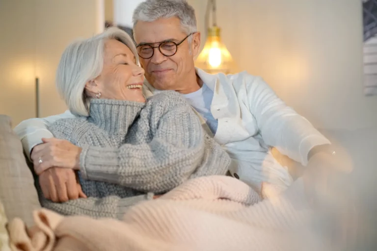 Lovely looking senior couple relaxing together on the couch at home thinking about the 6 Keys to Enhanced Attic Insulation