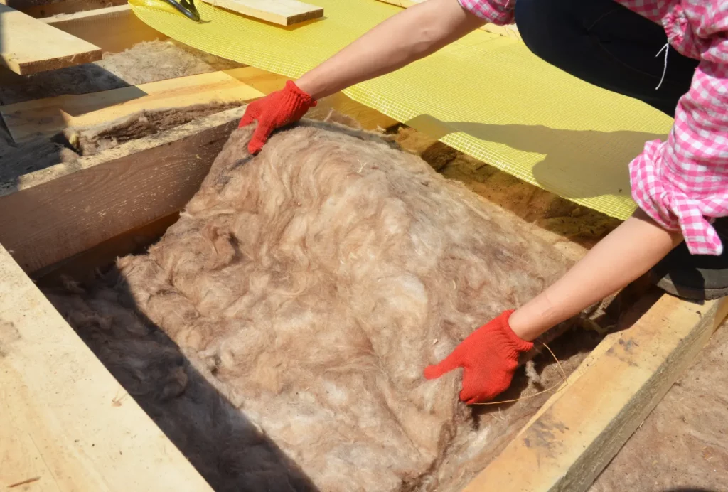 Roof-Attic Insulation: Roofer installing house roof thermal insulation with Mineral Wool, incorporating valuable Ventilation Tips for a healthier home environment.