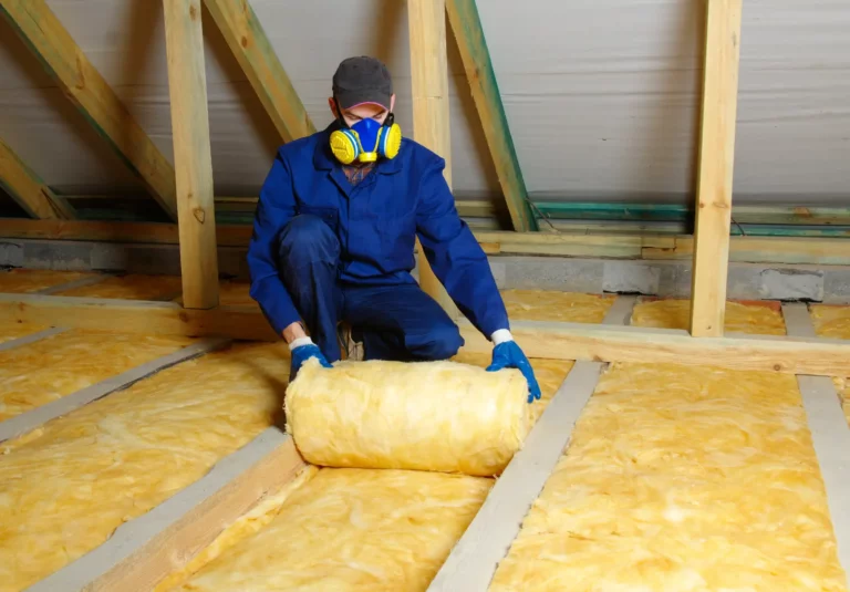 Skilled worker thermally insulating house attic with efficient glass wool insulation for optimal energy savings.