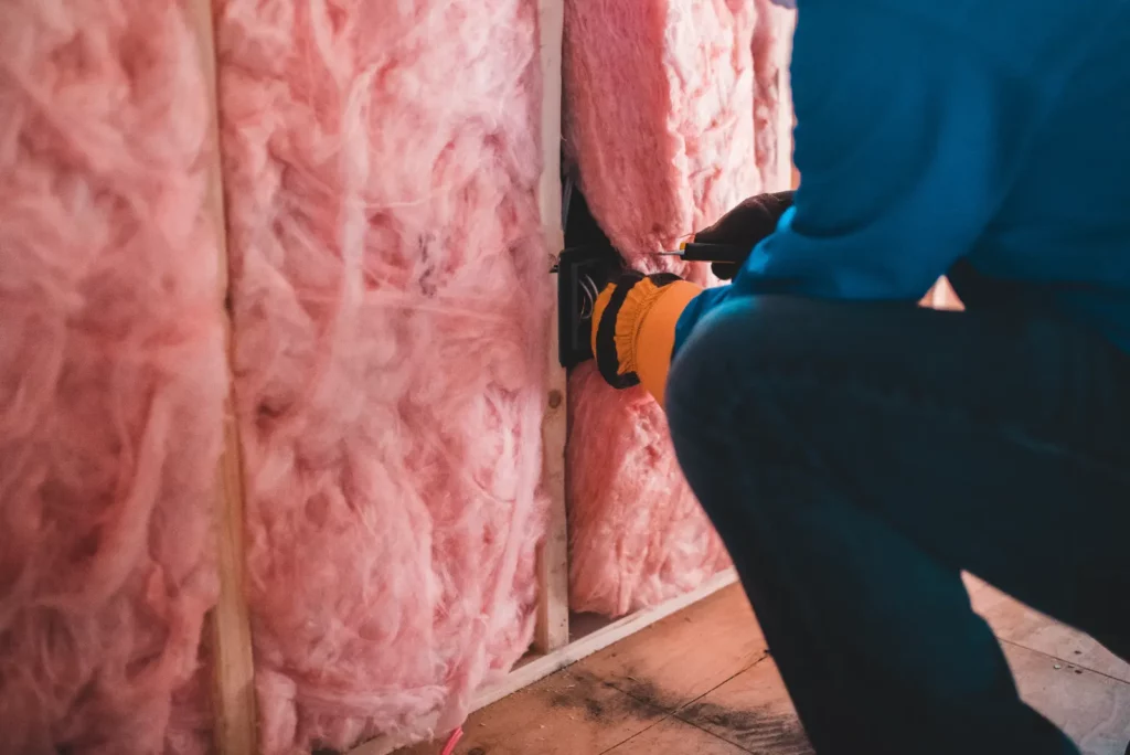 Closeup of a professional pushing insulation into place. Ensuring a secure and healthy living space with a Safe Roof Ventilation.