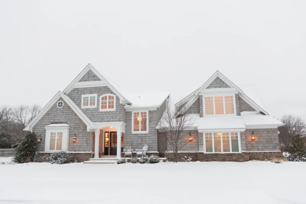 Family home surrounded by snow. Optimize your upstairs insulation with expert Tips for an energy-efficient and cozy home.